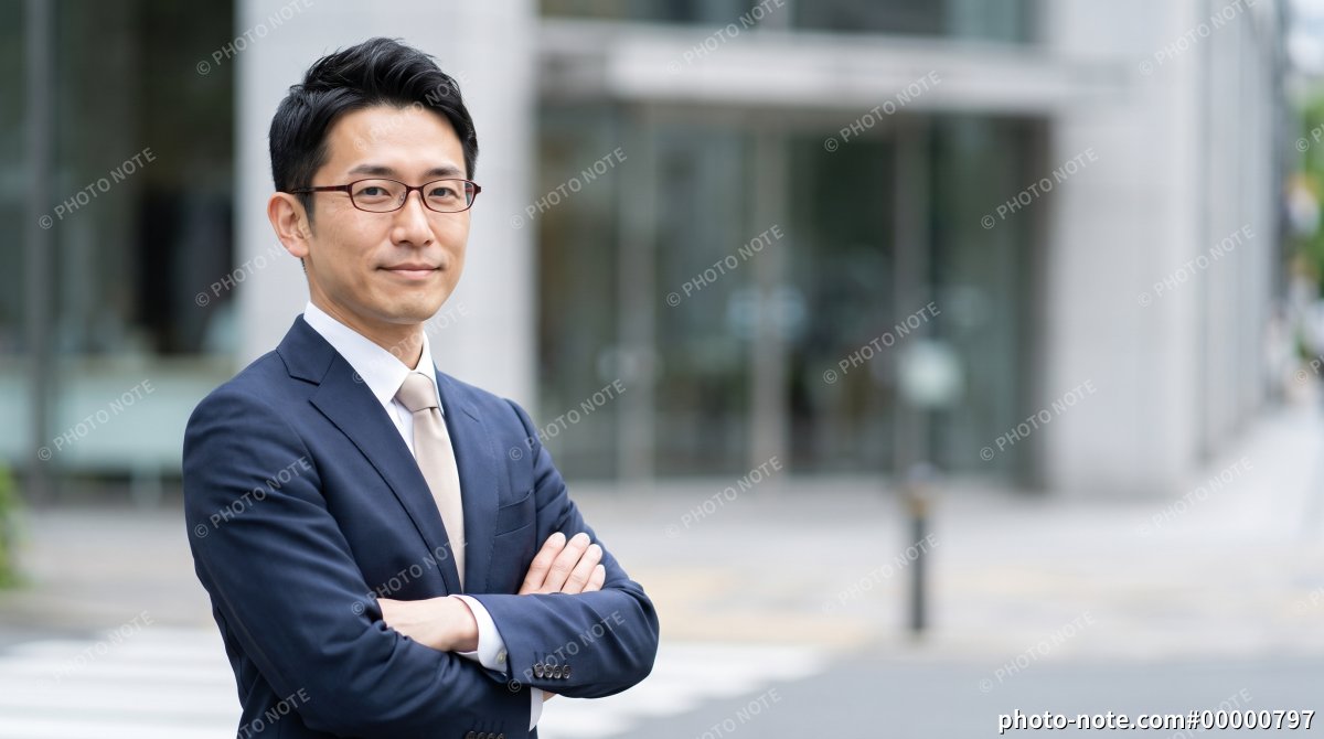 オフィス街で腕組みして立つ男性ビジネスマン