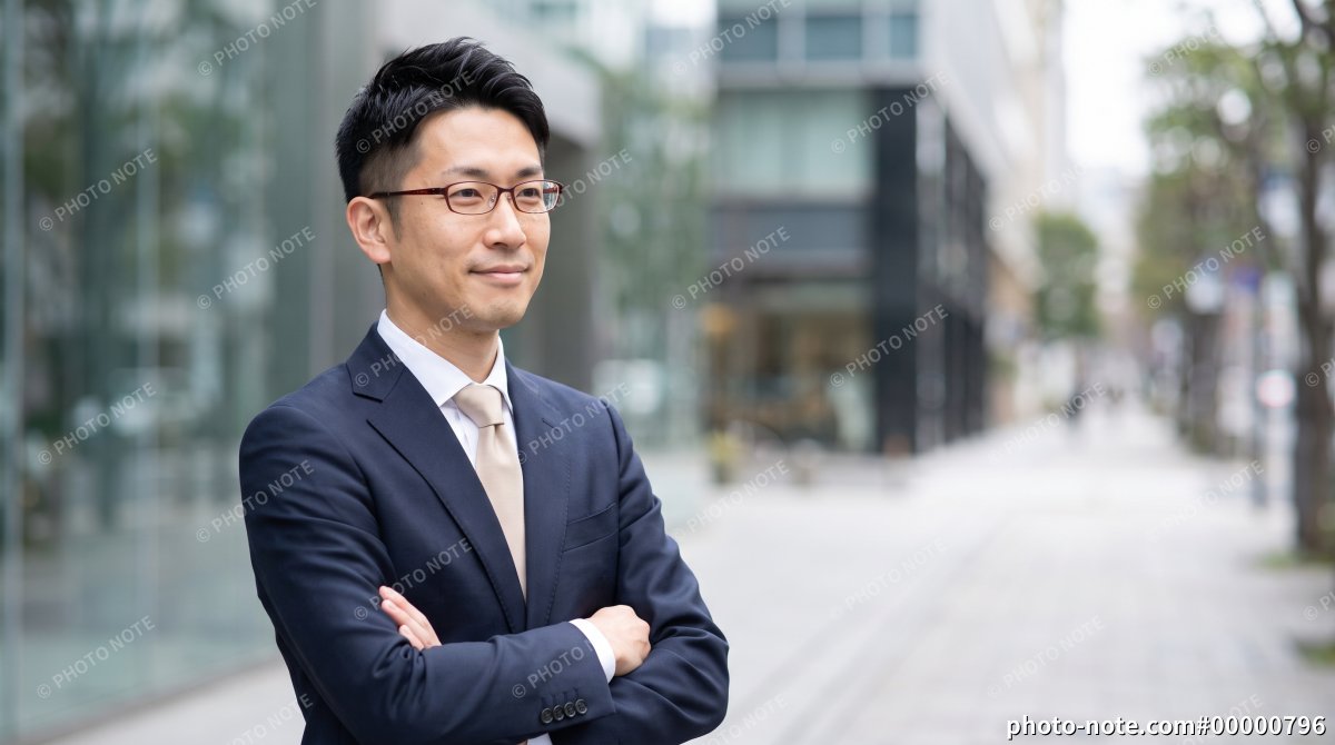 オフィス街で腕組みして立つ男性ビジネスマン
