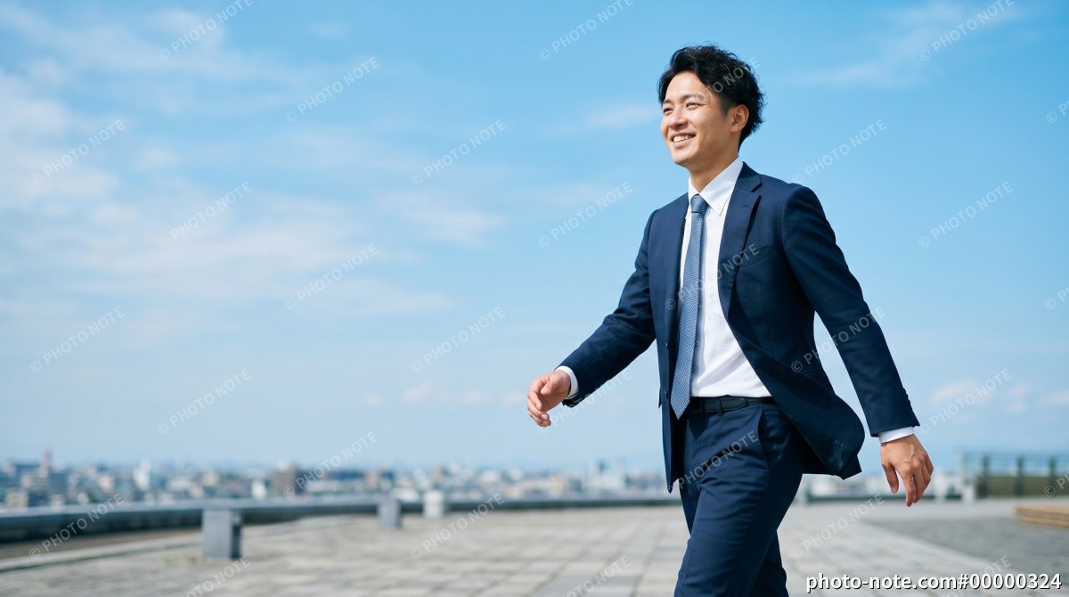 ビルの屋上を歩くスーツ姿の男性