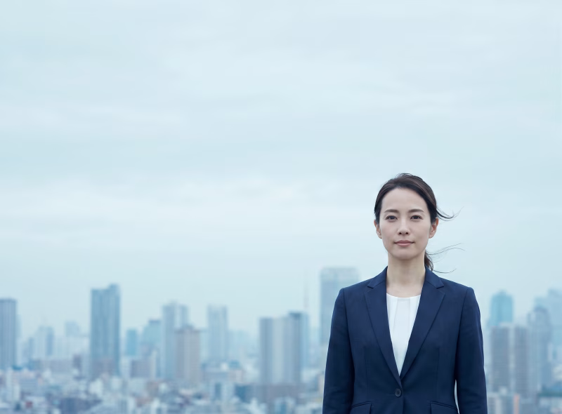 都市を背景に立つスーツ姿の女性ビジネスパーソン