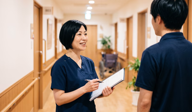 介護施設の廊下で打合せをするサービス責任者の女性
