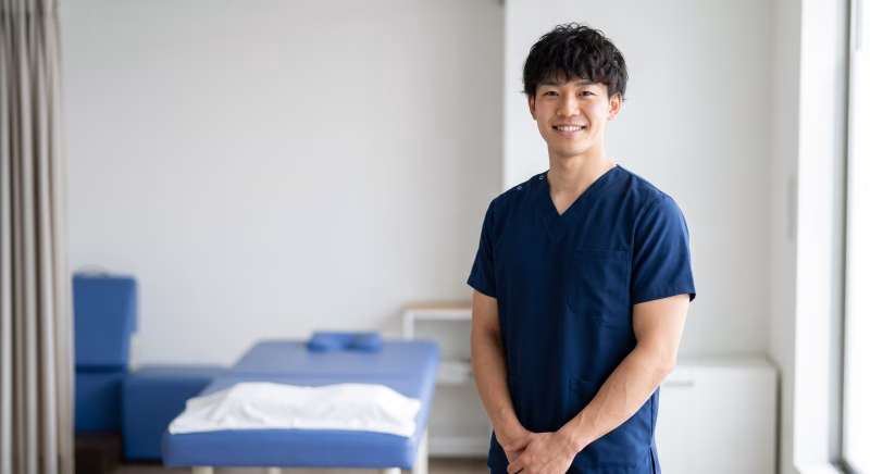 診察ベッドの前に立つ理学療法士の男性