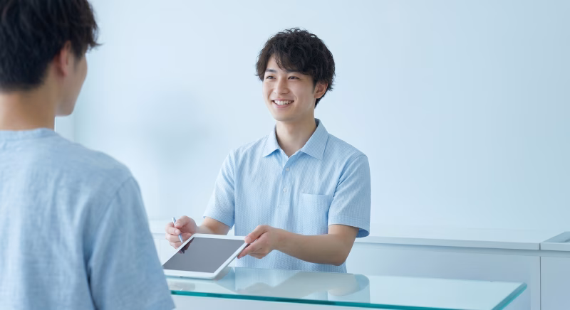 受付でタブレット端末を提示する男性スタッフ