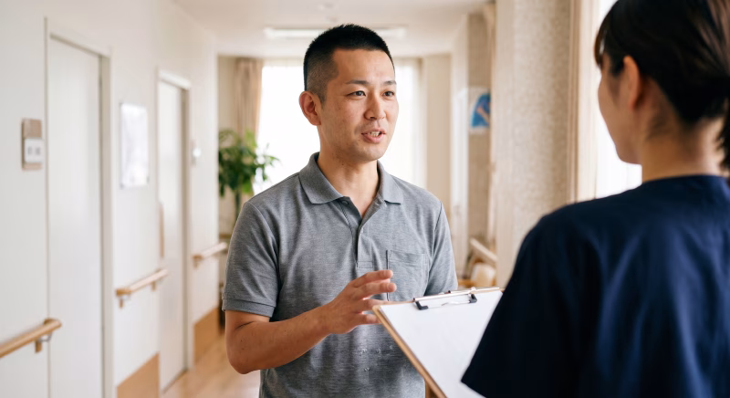 介護施設の廊下で打合せをするサービス責任者の男性