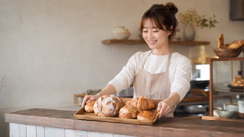 焼きたてのパンを並べる笑顔の女性