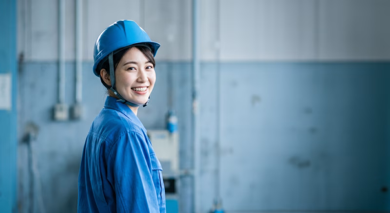 工場で振り返り笑顔の女性作業員