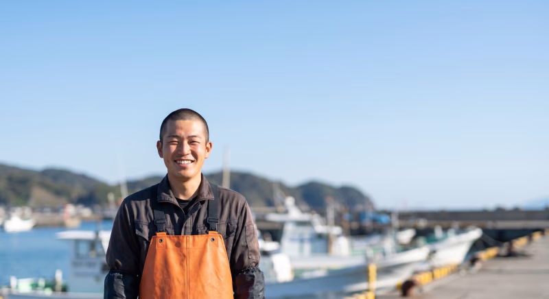 漁港で笑顔を見せる作業服姿の漁師