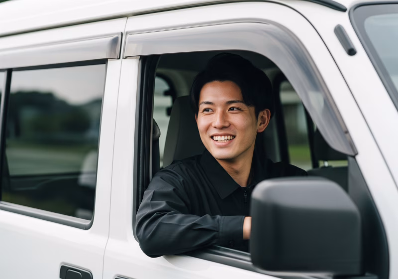 運転席から笑顔を見せる男性ドライバー