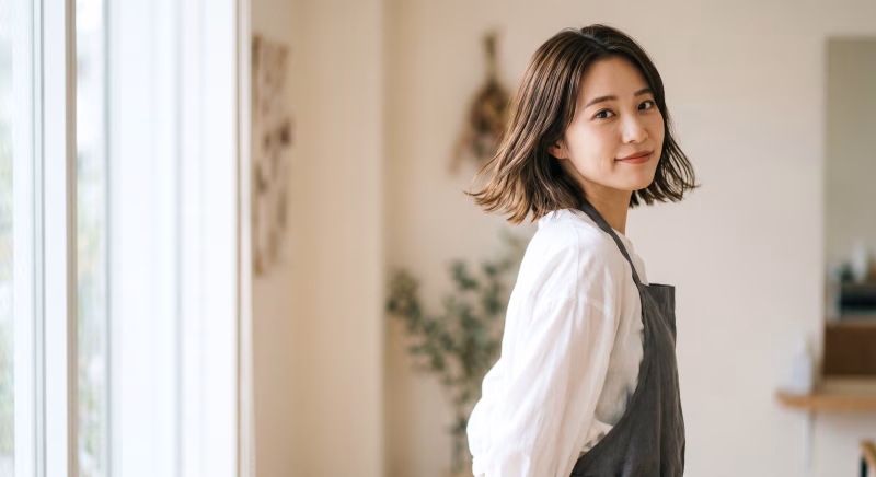 サロンで働くエプロン姿の若い女性スタッフ 美容師 カフェ店員