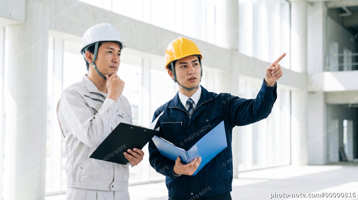 建設現場で設備を指差しながら確認する施工管理スタッフ