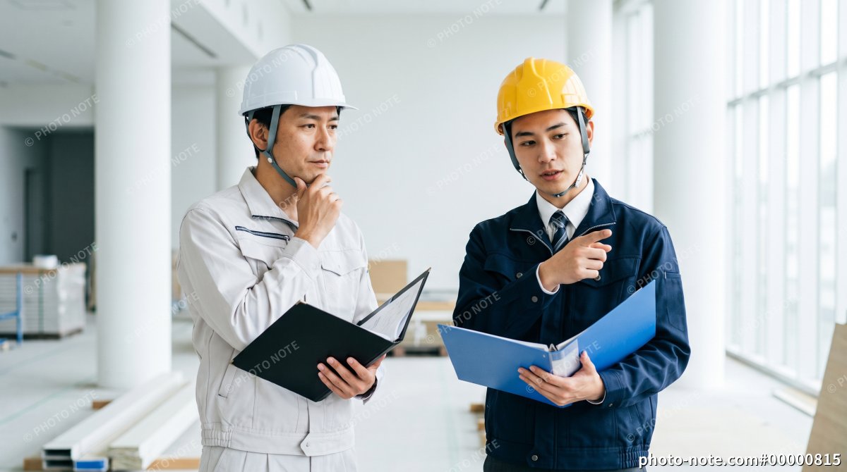 建設現場で資料を確認しながら打ち合わせをする施工管理スタッフ
