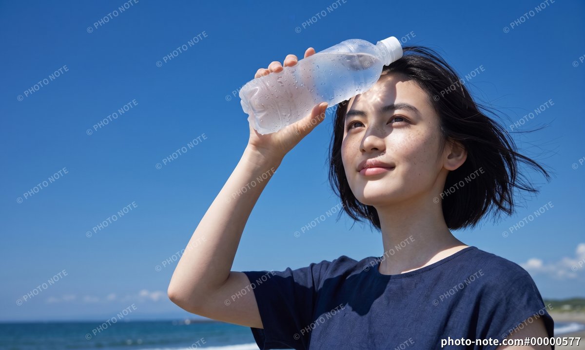 夏の海辺で冷たい水のペットボトルを額に当てる女性