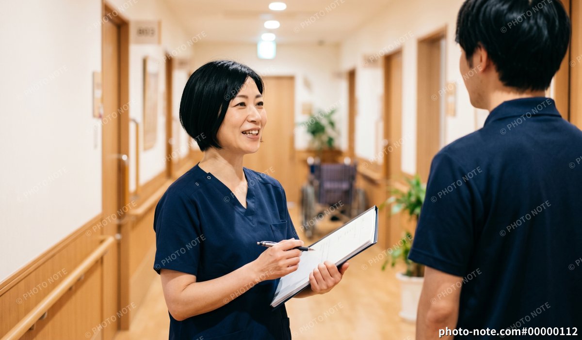 介護施設の廊下で打合せをするサービス責任者の女性