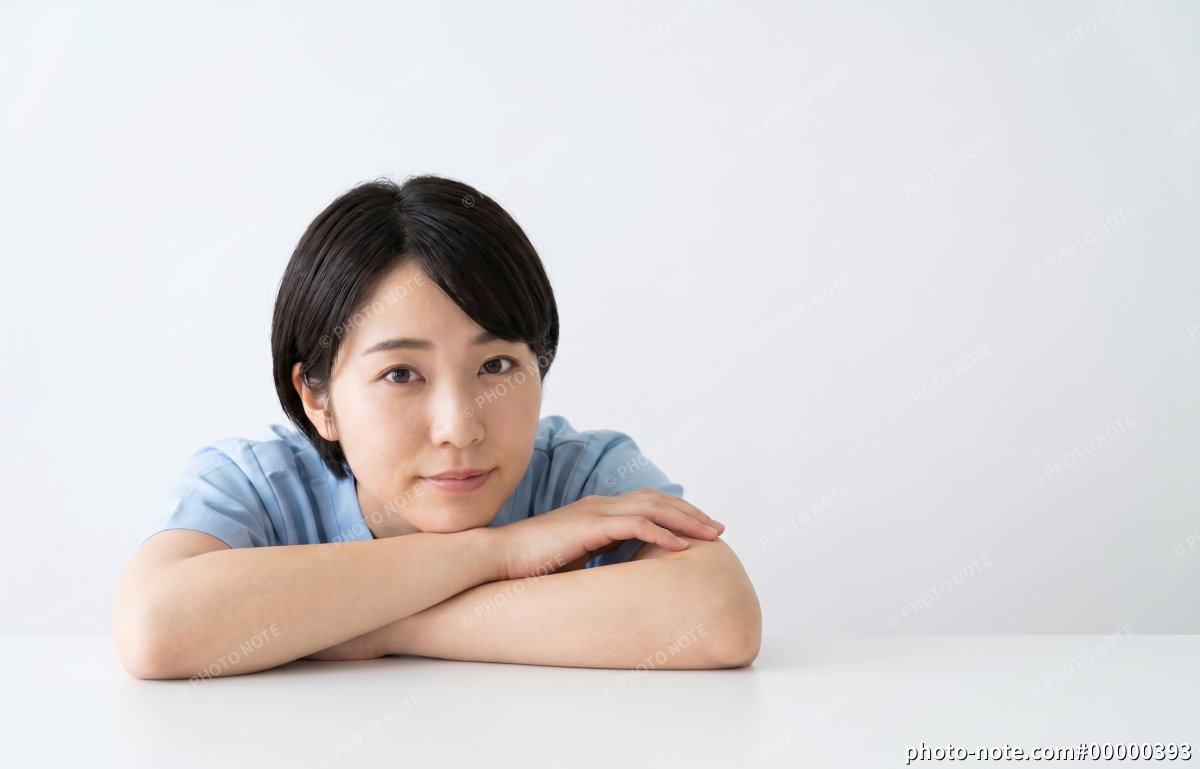 テーブルに腕を置いて正面を見つめる医療・介護スタッフの女性