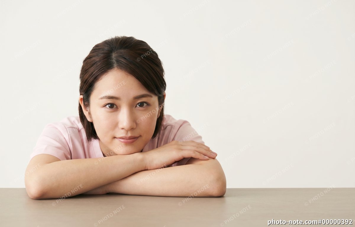 テーブルに腕を置いて正面を見つめる医療・介護スタッフの女性