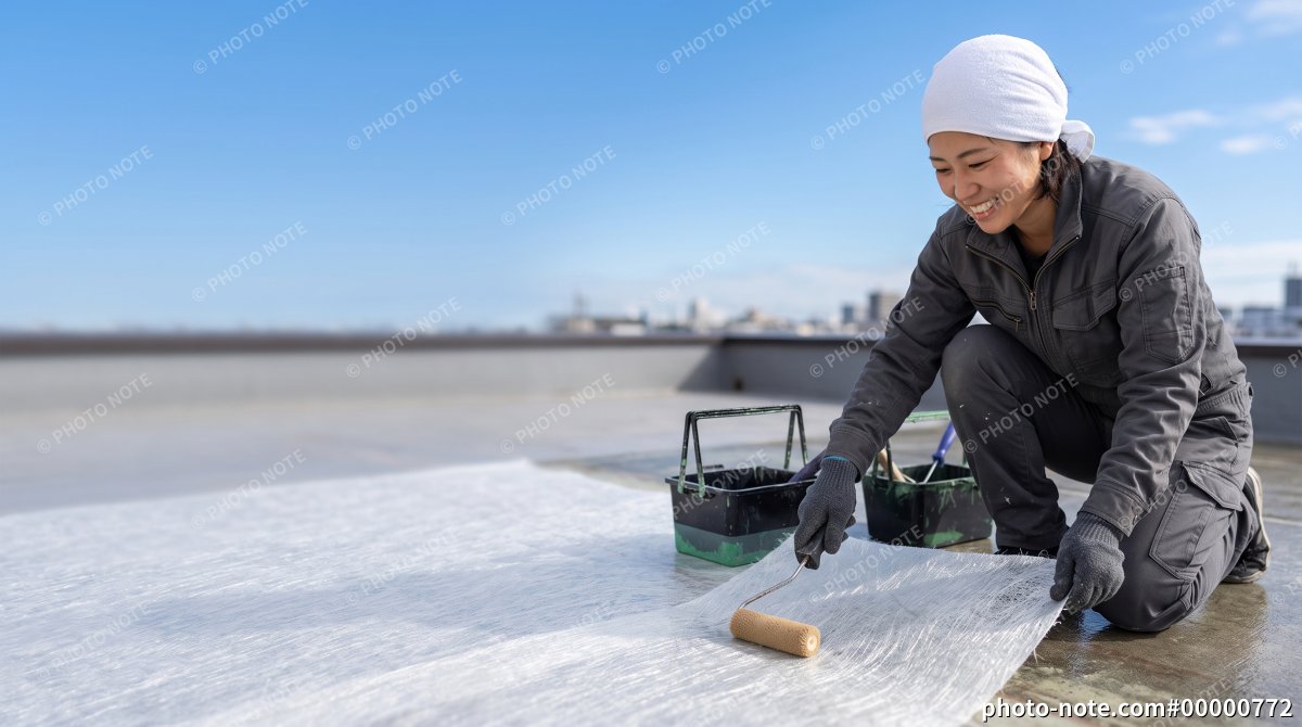 屋上でローラーを使って防水シートを施工する女性職人