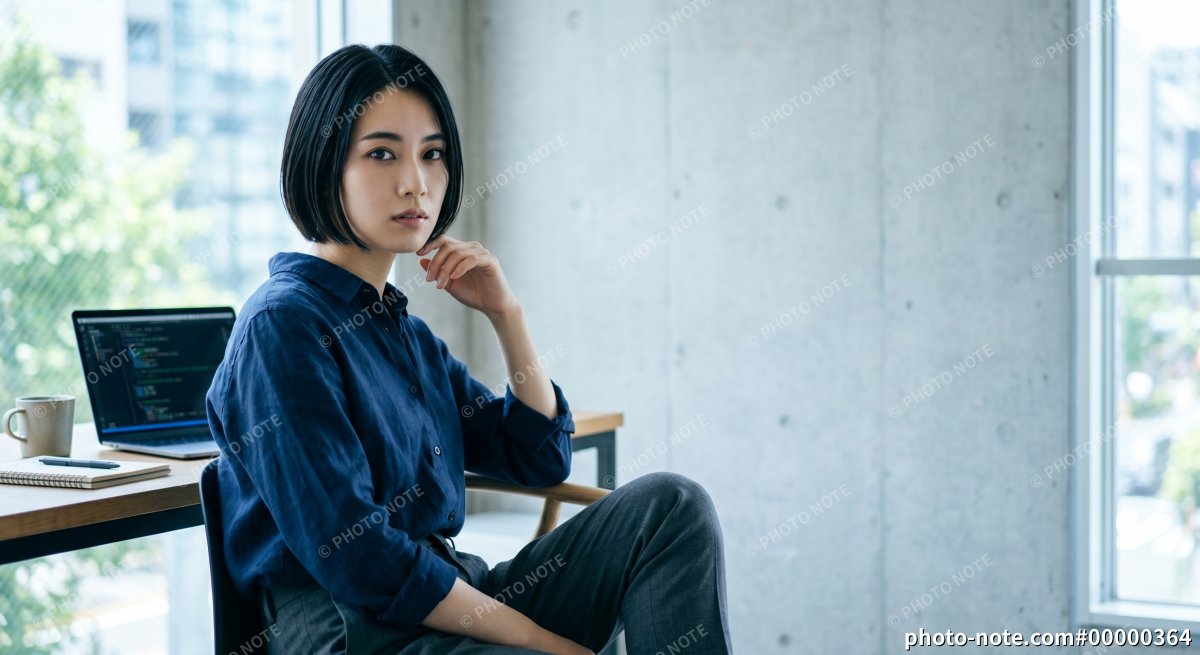 コードが表示されたノートパソコンと若い女性エンジニア