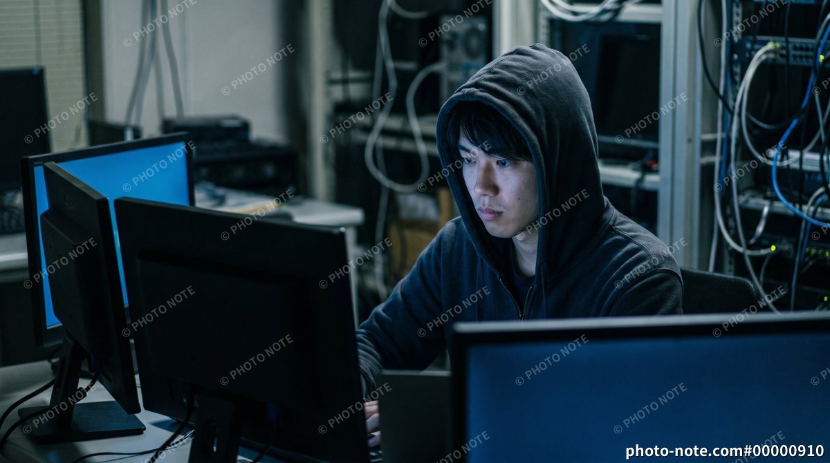 サーバー室で複数のパソコンを操作するハッカーの男性