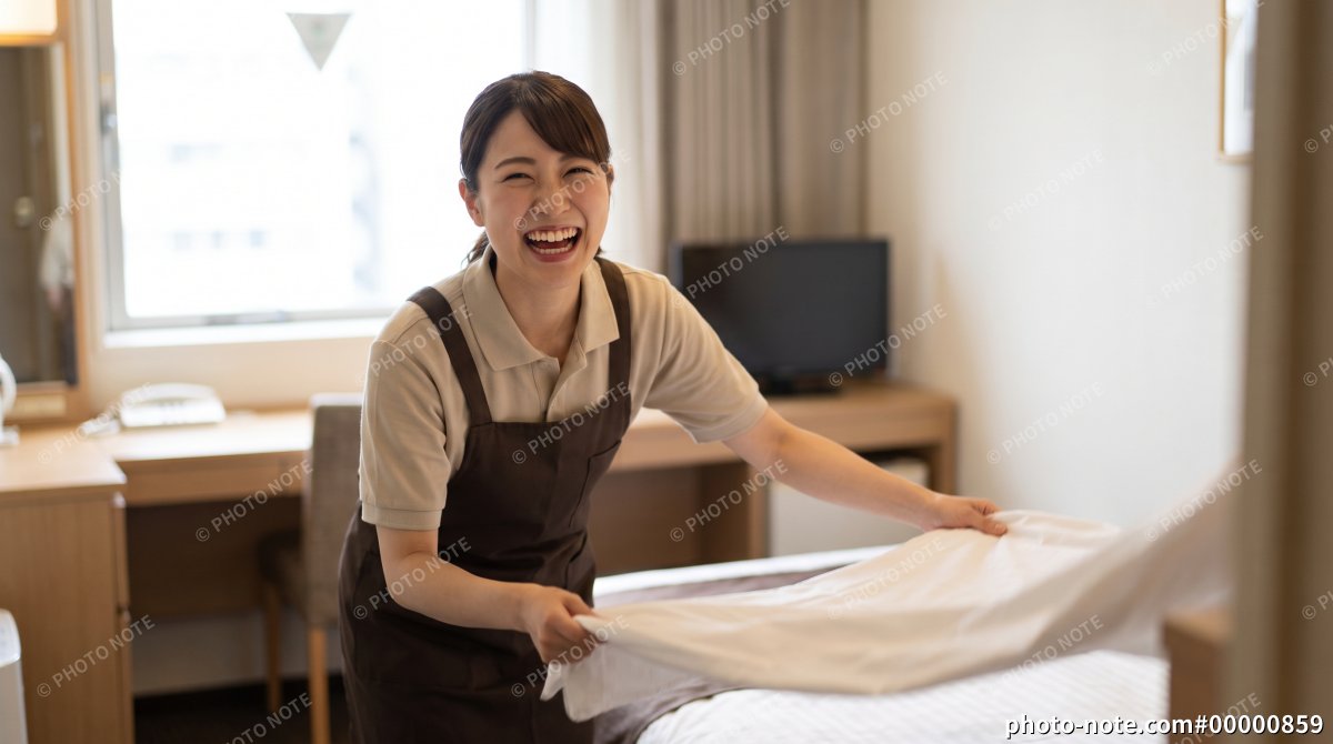 ホテルの客室でシーツを整える女性清掃スタッフ