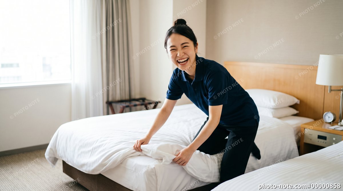 ホテルの客室でベッドメイクをする笑顔の女性スタッフ