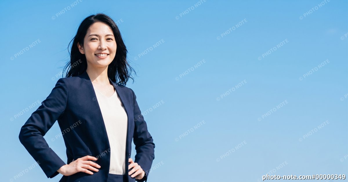 青空を背景にしたスーツ姿の日本人女性