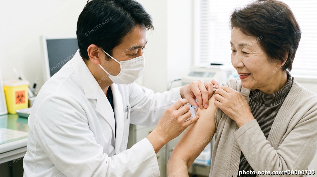 高齢女性の上腕にワクチンを接種する日本人男性医師