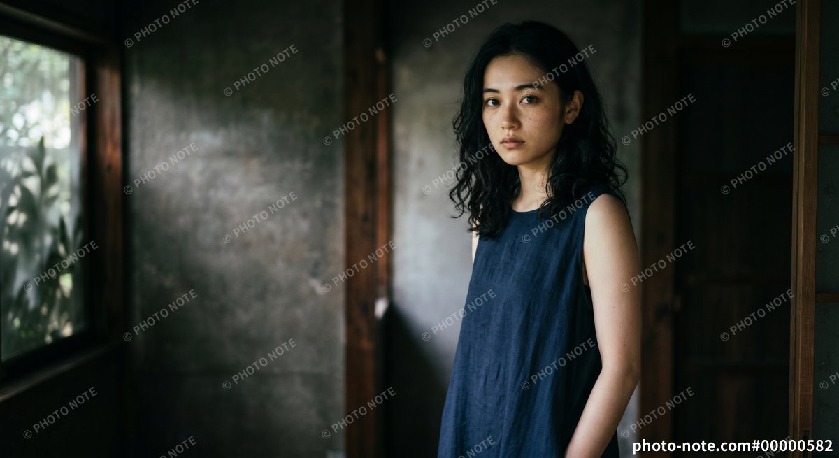 古民家の室内で静かにカメラを見つめるノースリーブ姿の日本人女性