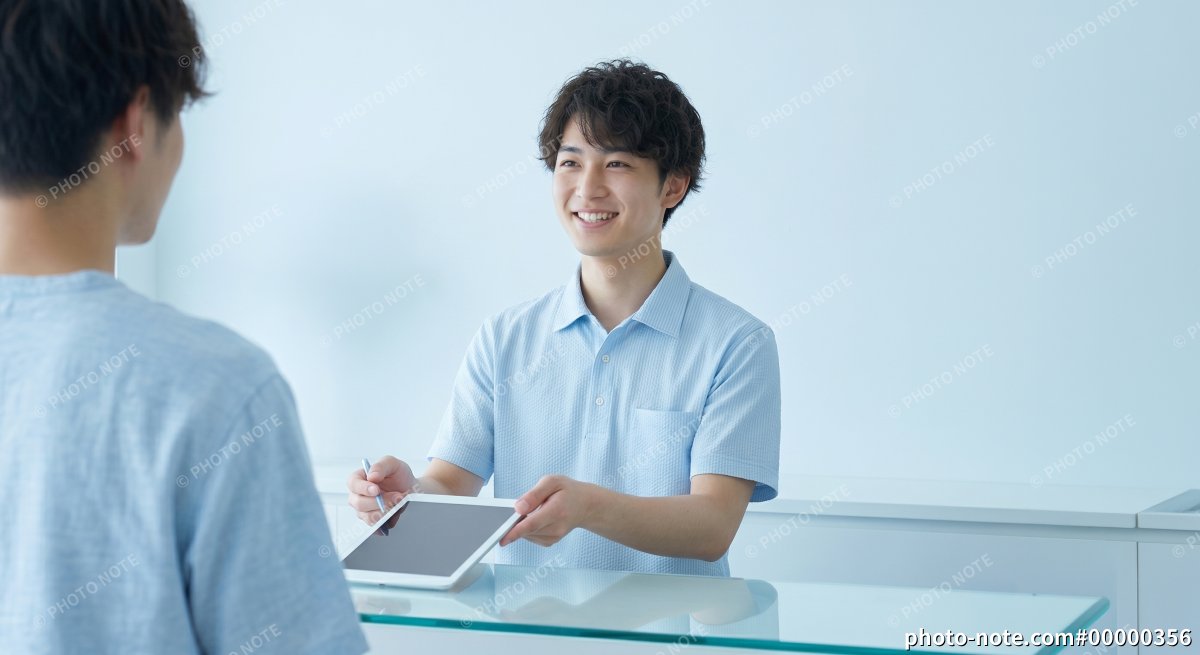 受付でタブレット端末を提示する男性スタッフ