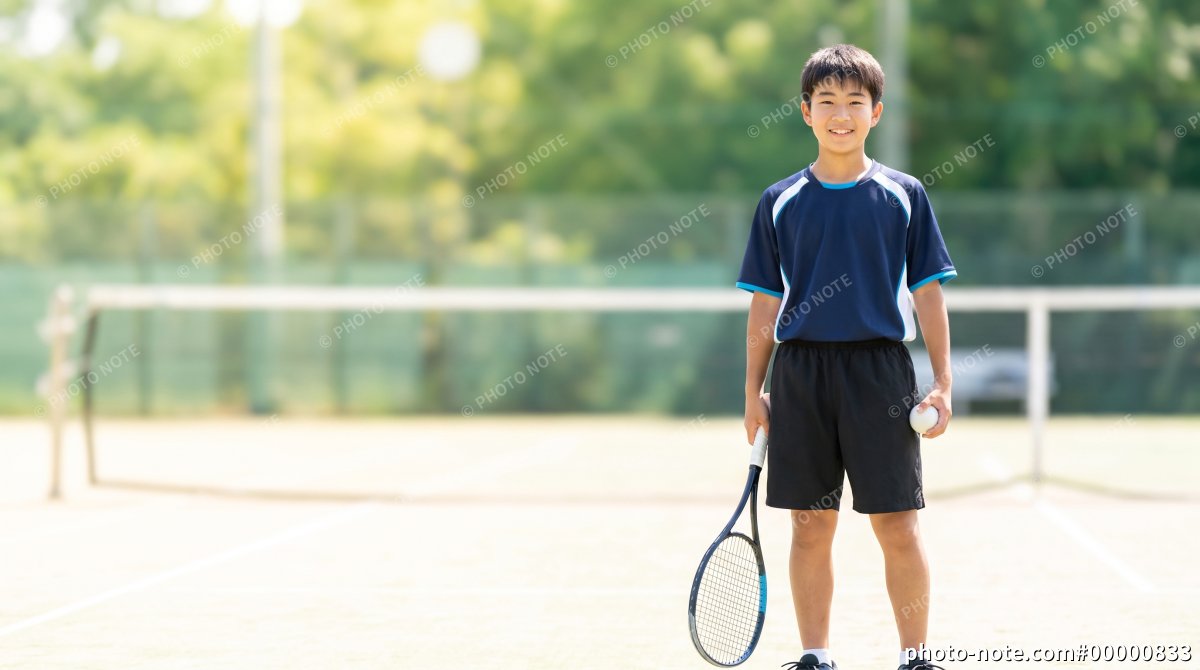 ソフトテニスのラケットとボールを持つ10代の男子学生