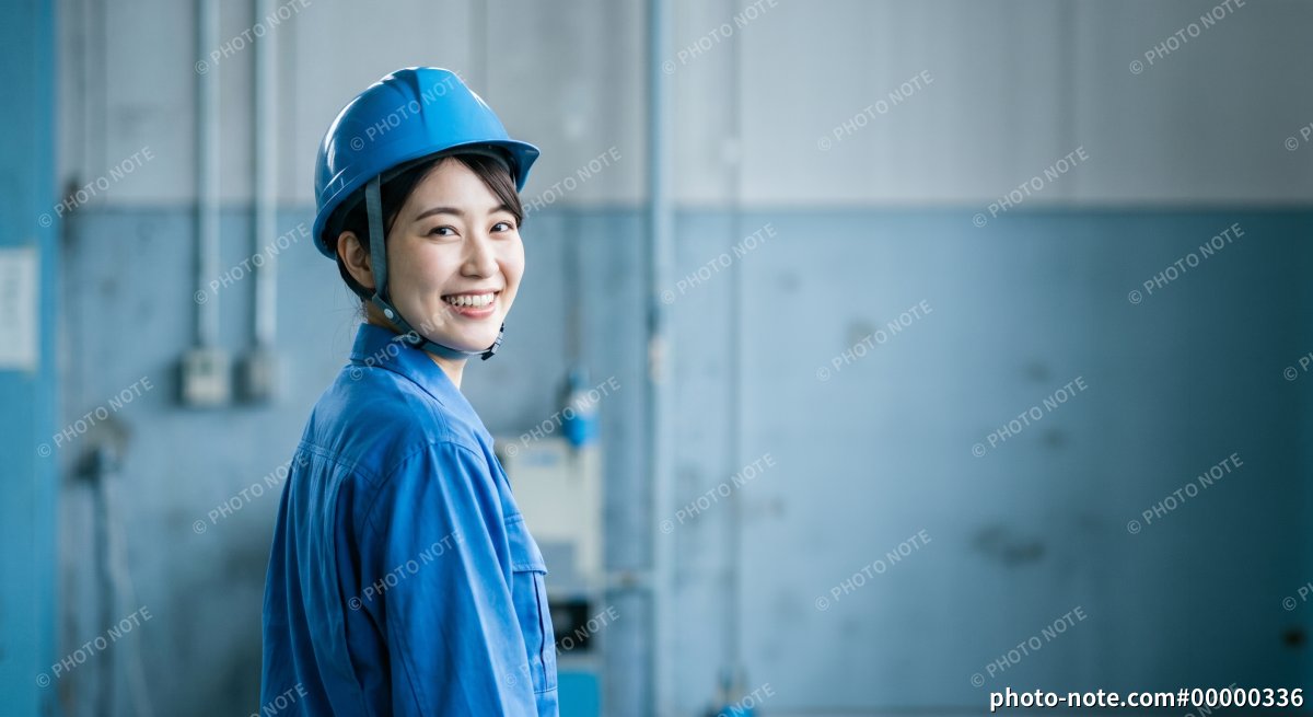 工場で振り返り笑顔の女性作業員