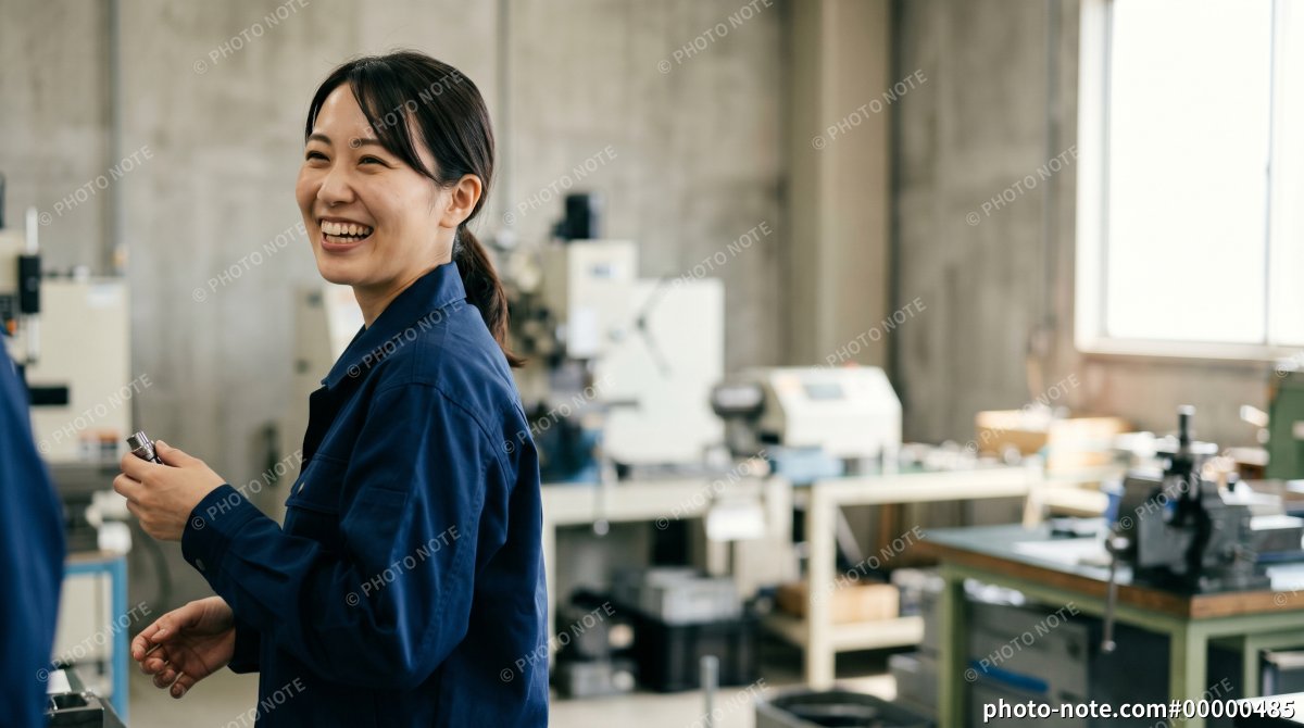 工場で作業をしながら笑顔を見せる女性スタッフ