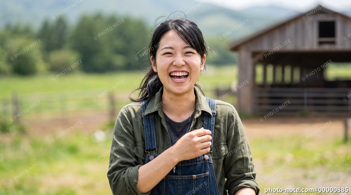 牧場で笑顔を見せるオーバーオール姿の若い女性酪農スタッフ