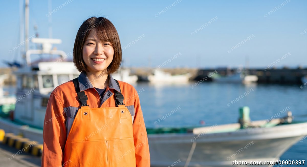 漁港で笑顔を見せる作業服姿の女性漁師