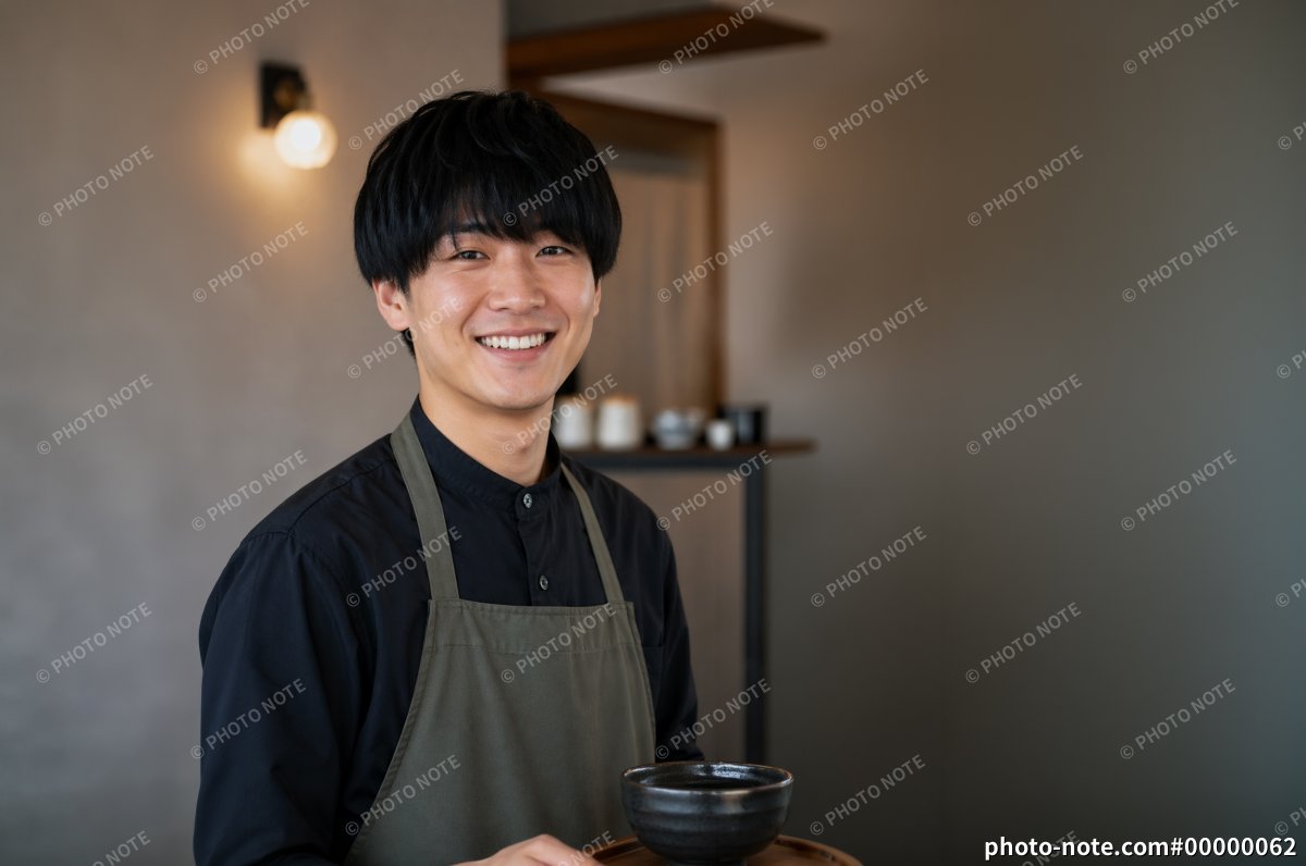 飲食店で料理を運ぶ笑顔の若い男性スタッフ、カフェ店員