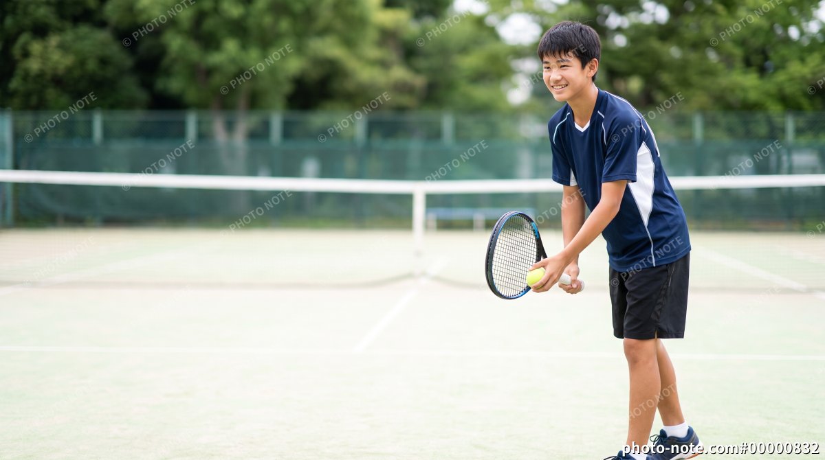 テニスコートでサーブをする10代の男子学生