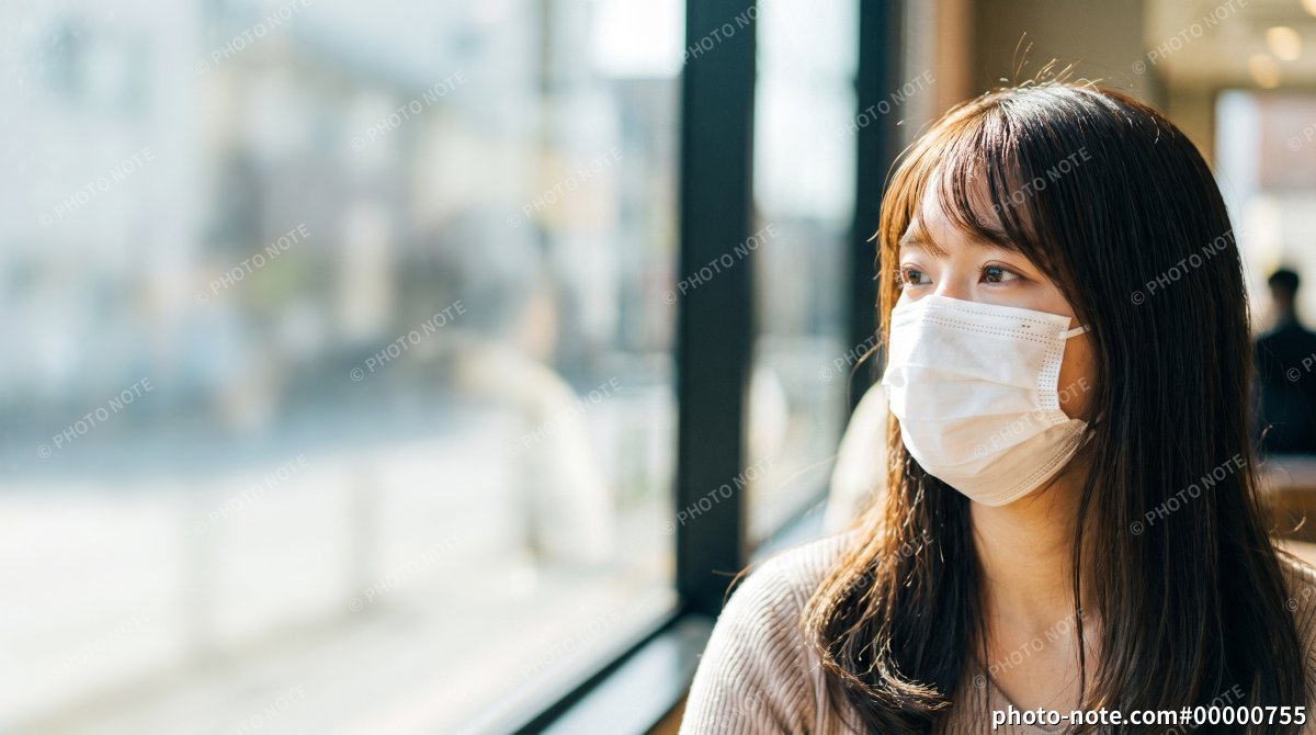 風邪や花粉症対策にマスクを着用しカフェで休む日本人女性