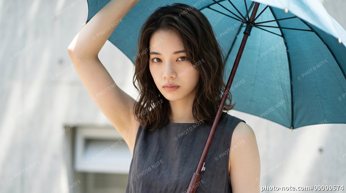 夏の屋外で青い日傘をさす若い女性