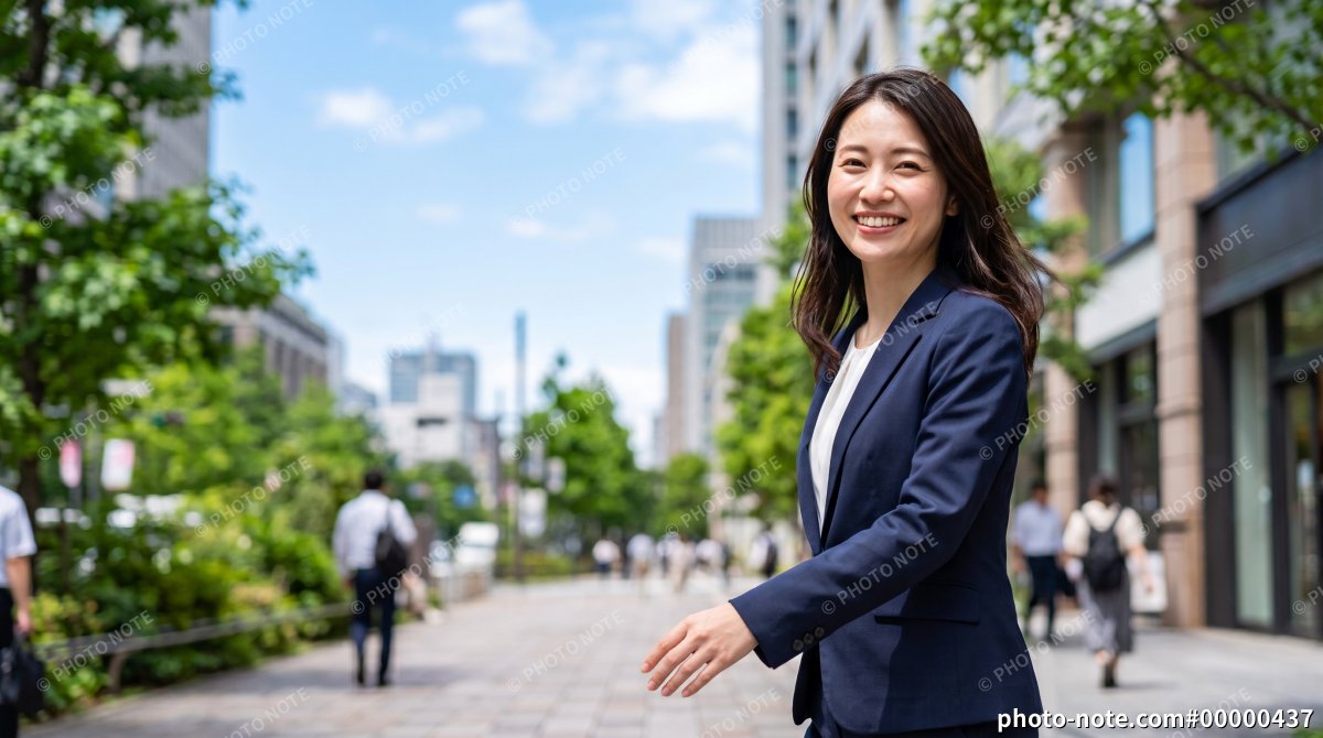 新緑のオフィス街を通勤するスーツ姿の若い女性会社員