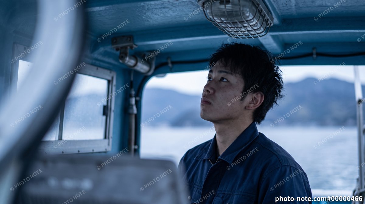 漁船を操縦する若い男性漁師