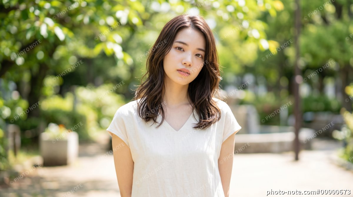 新緑の公園に立つ若い女性のポートレート