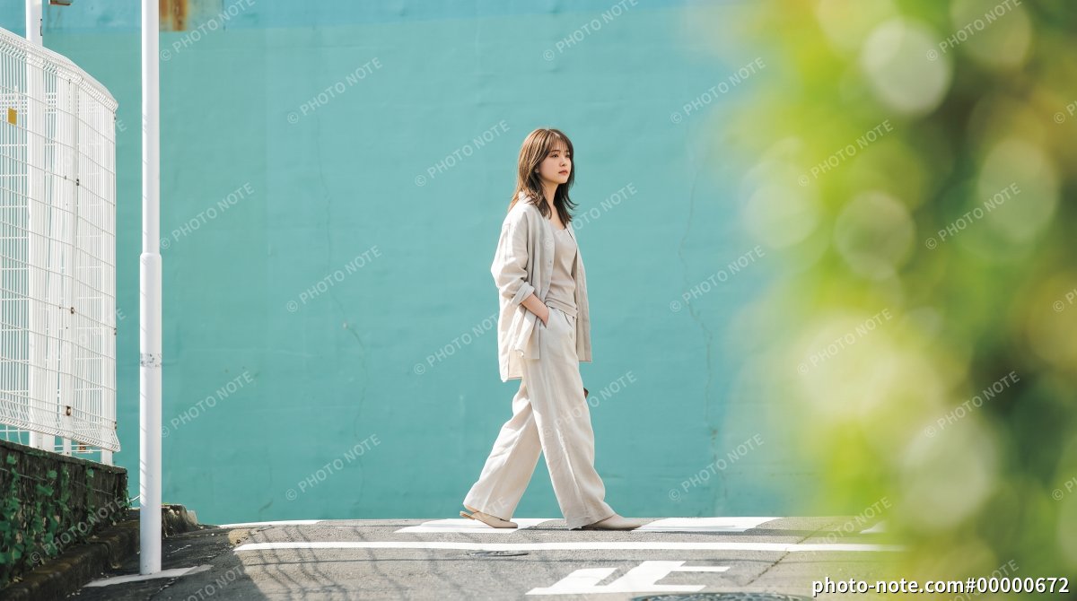 日本の街角を歩く、ベージュのセットアップを着た笑顔の若い女性